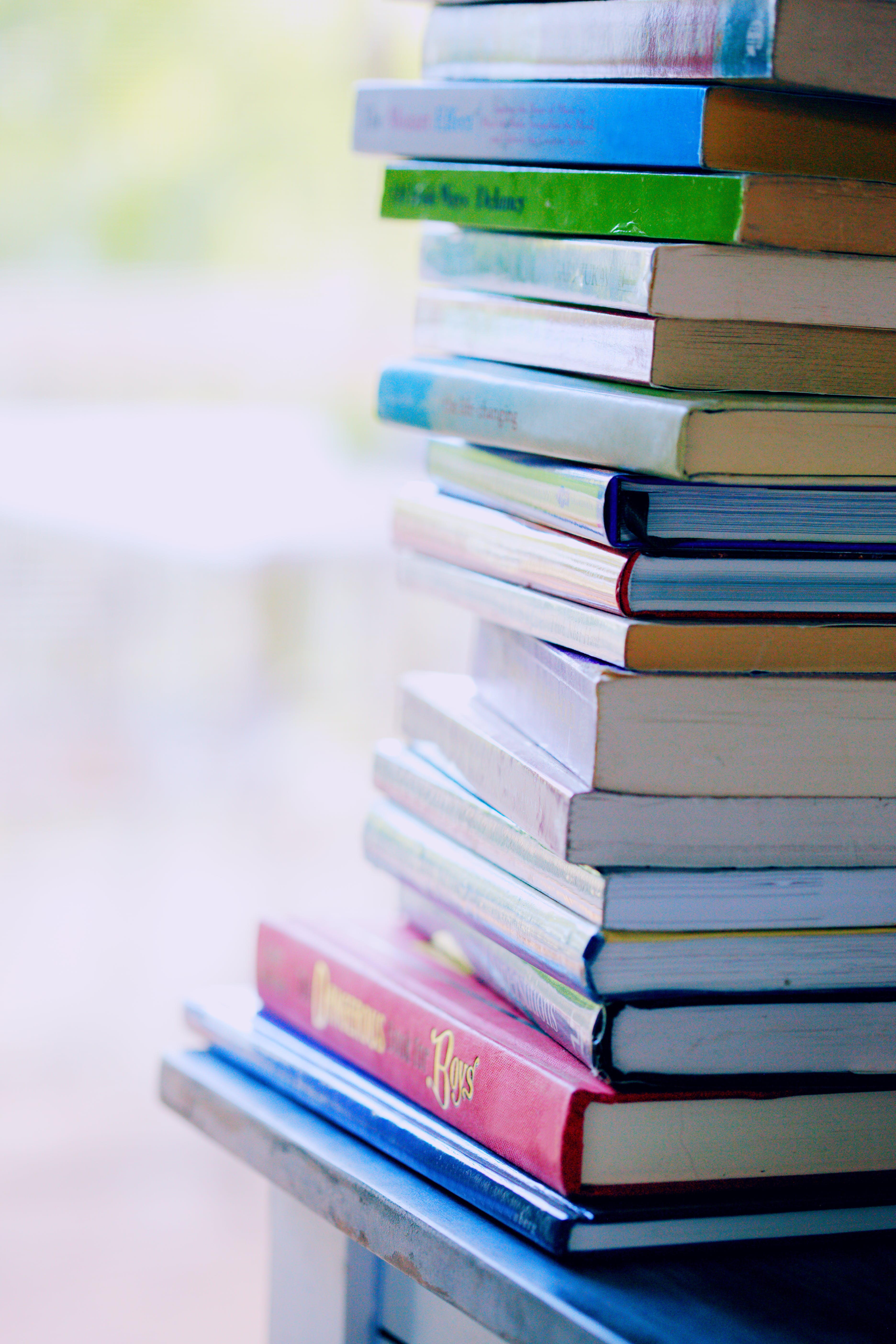Image of the bindings of a tall stack of books on the corner of a table.